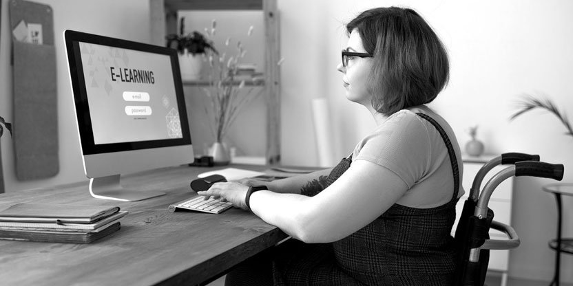 A woman in a wheelchair looks at a monitor which says eLearning.