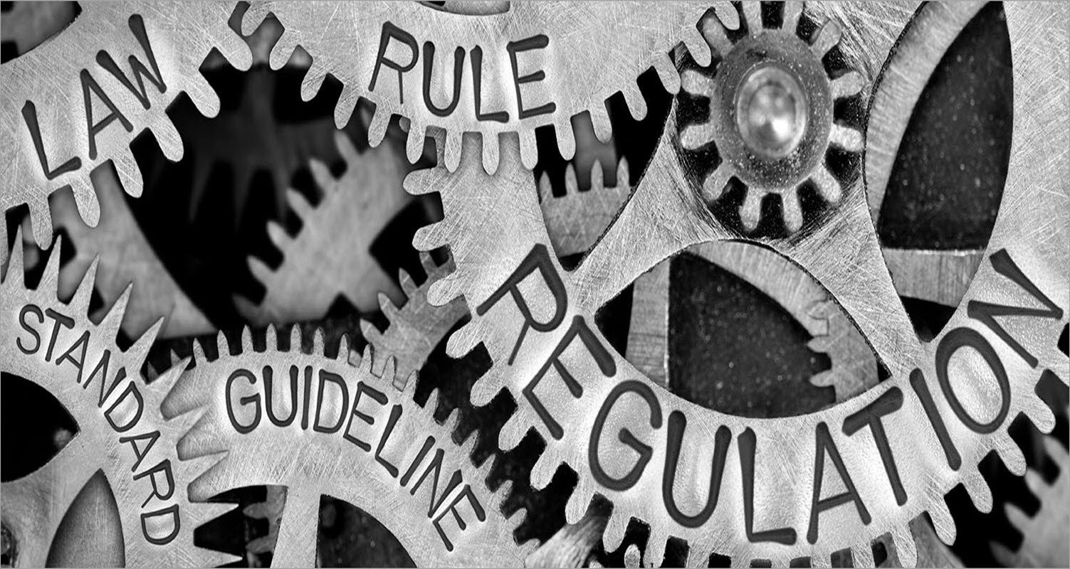 Cogs with words imprinted on them. Words shown are law, standard, rule, guideline and regulation.